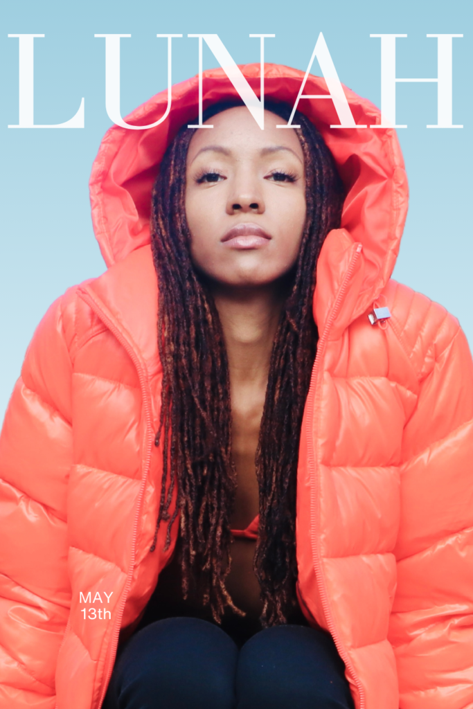 Soft light portrait of Lunah Moore sitting while wearing an orange, hooded coat